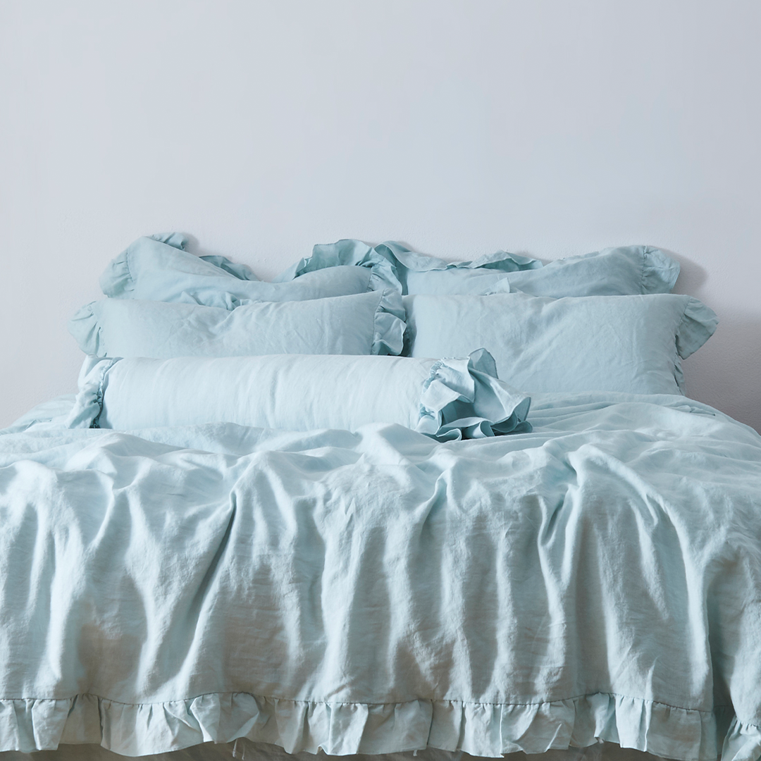 Pale Blue Linen Bolster Pillow with Ruffle Hem on Bed