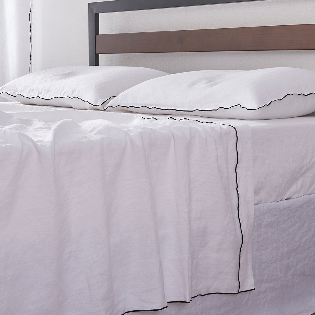 Bed with 100% Linen White Flat Sheet with Black Embroidered Edge and Pillows