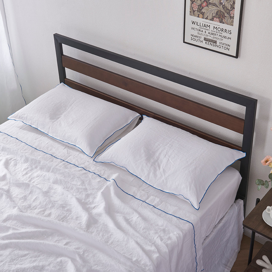 Pair of 100% Linen White Pillowcases with Brilliant Blue Embroidered Edge on Bed