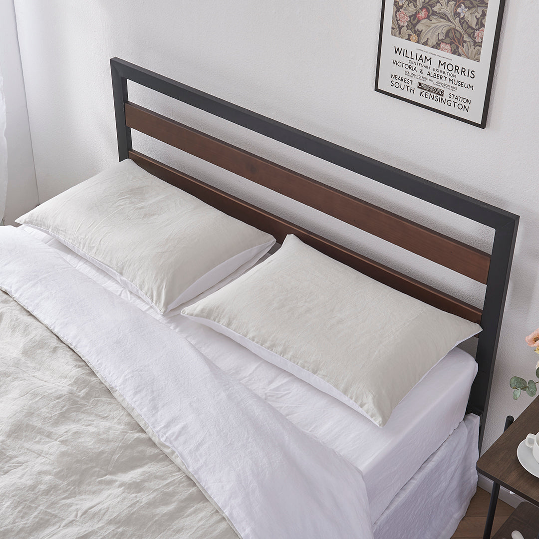 A pair of cool grey and white 100% linen two tone pillowcases lying flat on a bed