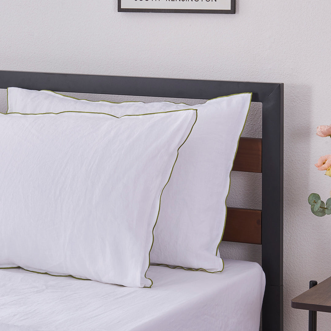 Pair of White Linen Pillowcases with Leek Green Embroidered Edge on Bed