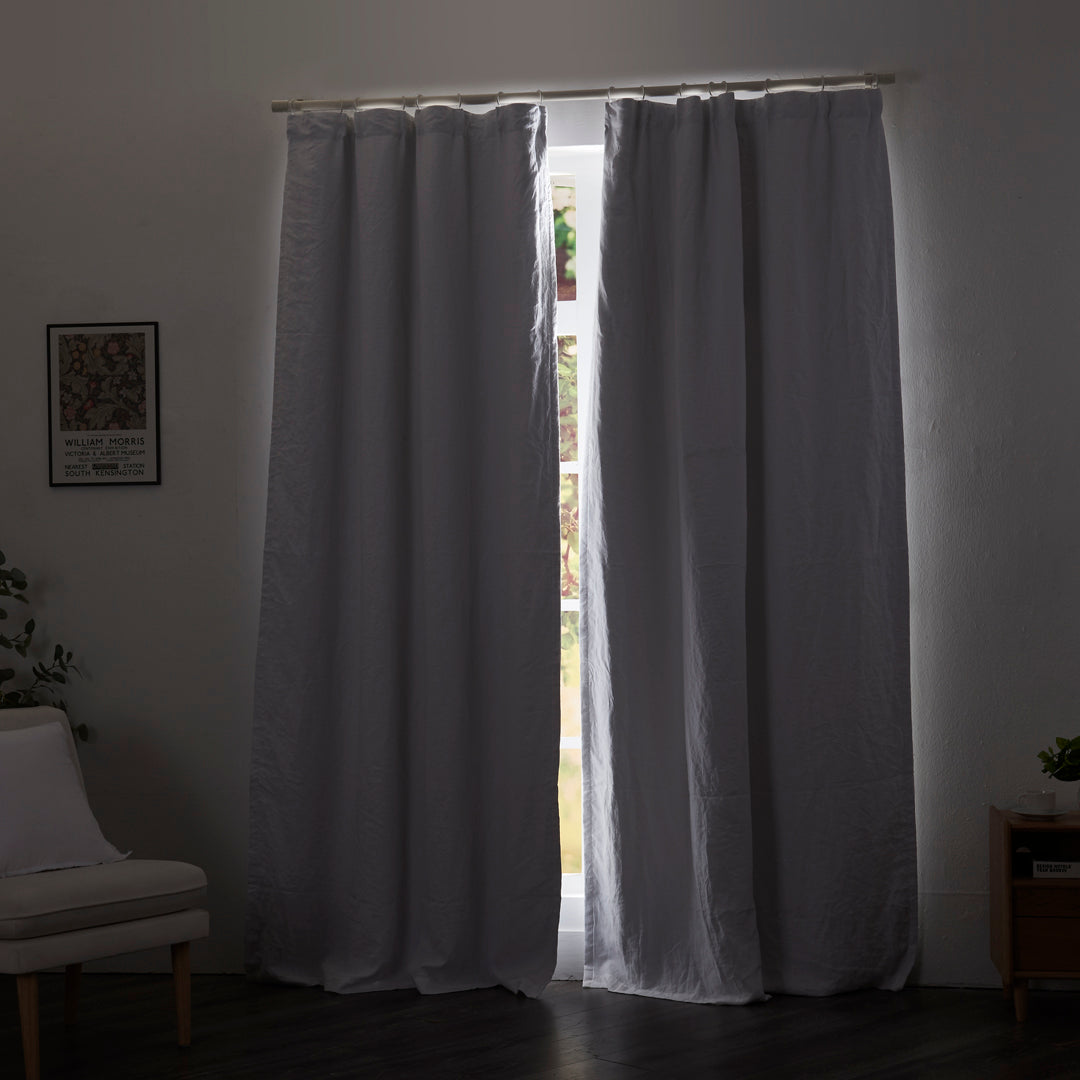 Optic white linen drapery with blackout lining drawn closed over windows