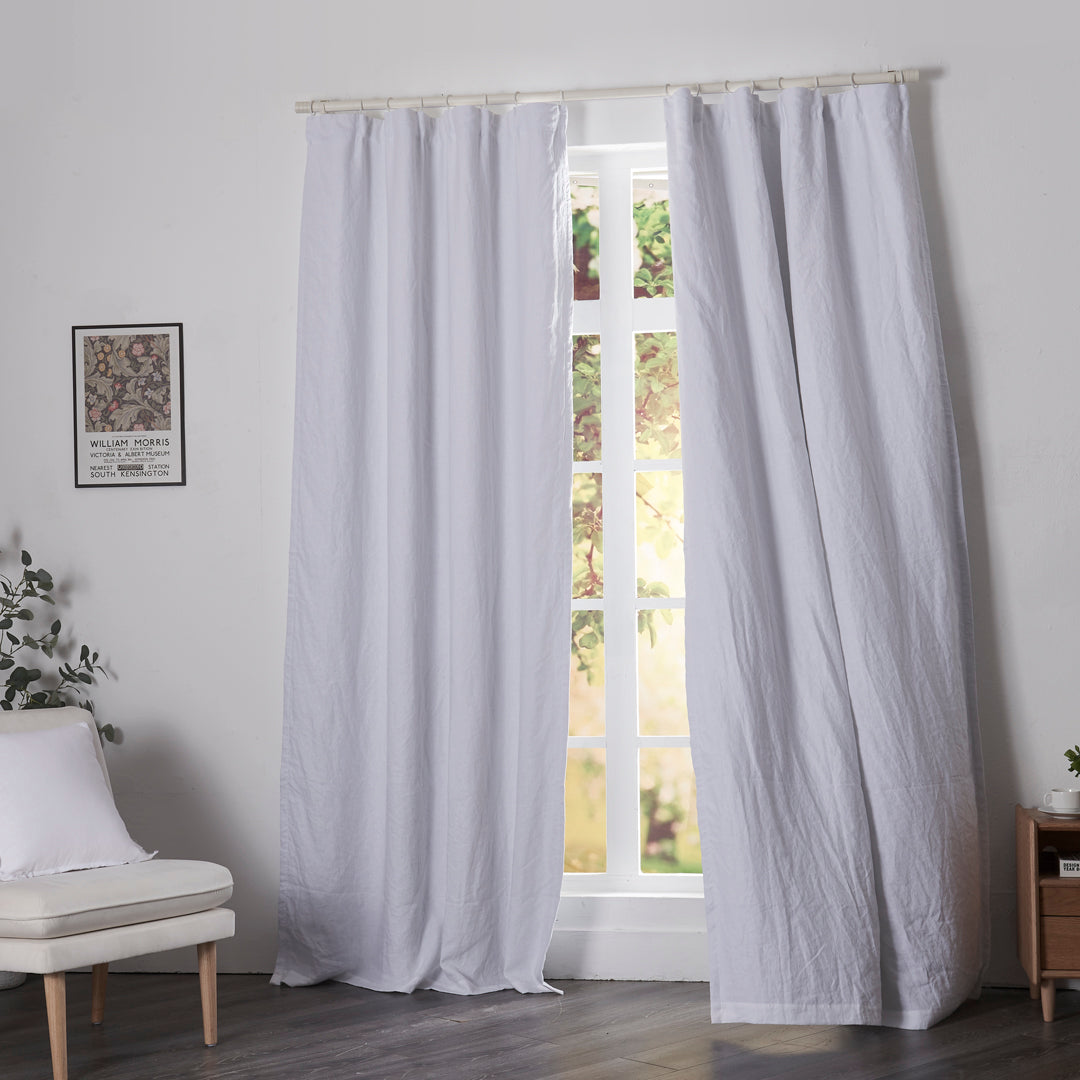Optic white linen drapery with blackout lining billowing over windows