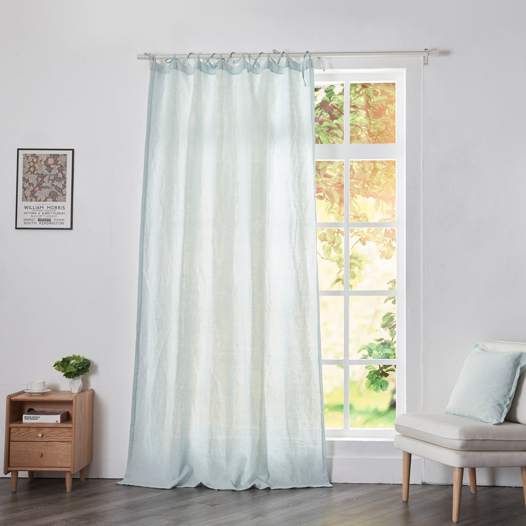 Pale blue linen drapery with tie tops hanging over windows