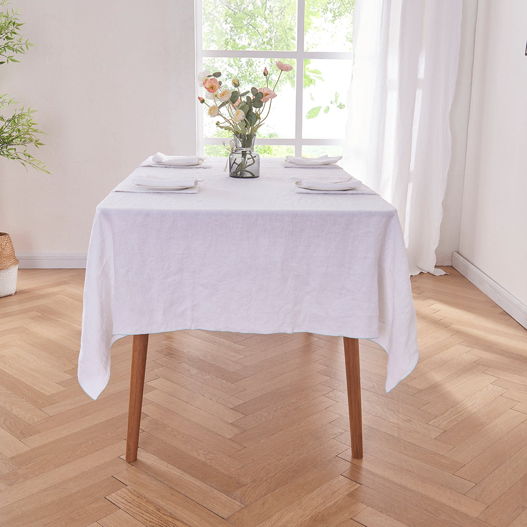White Linen Tablecloth with Pale Blue Embroidered Edge on Table