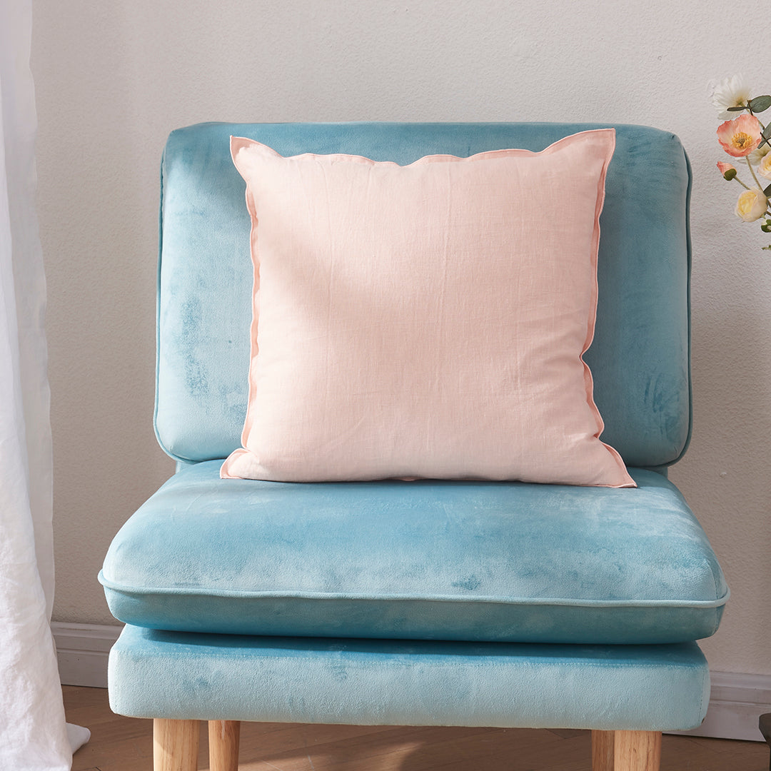 A peach 100% linen edge embroidery cushion on an accent chair