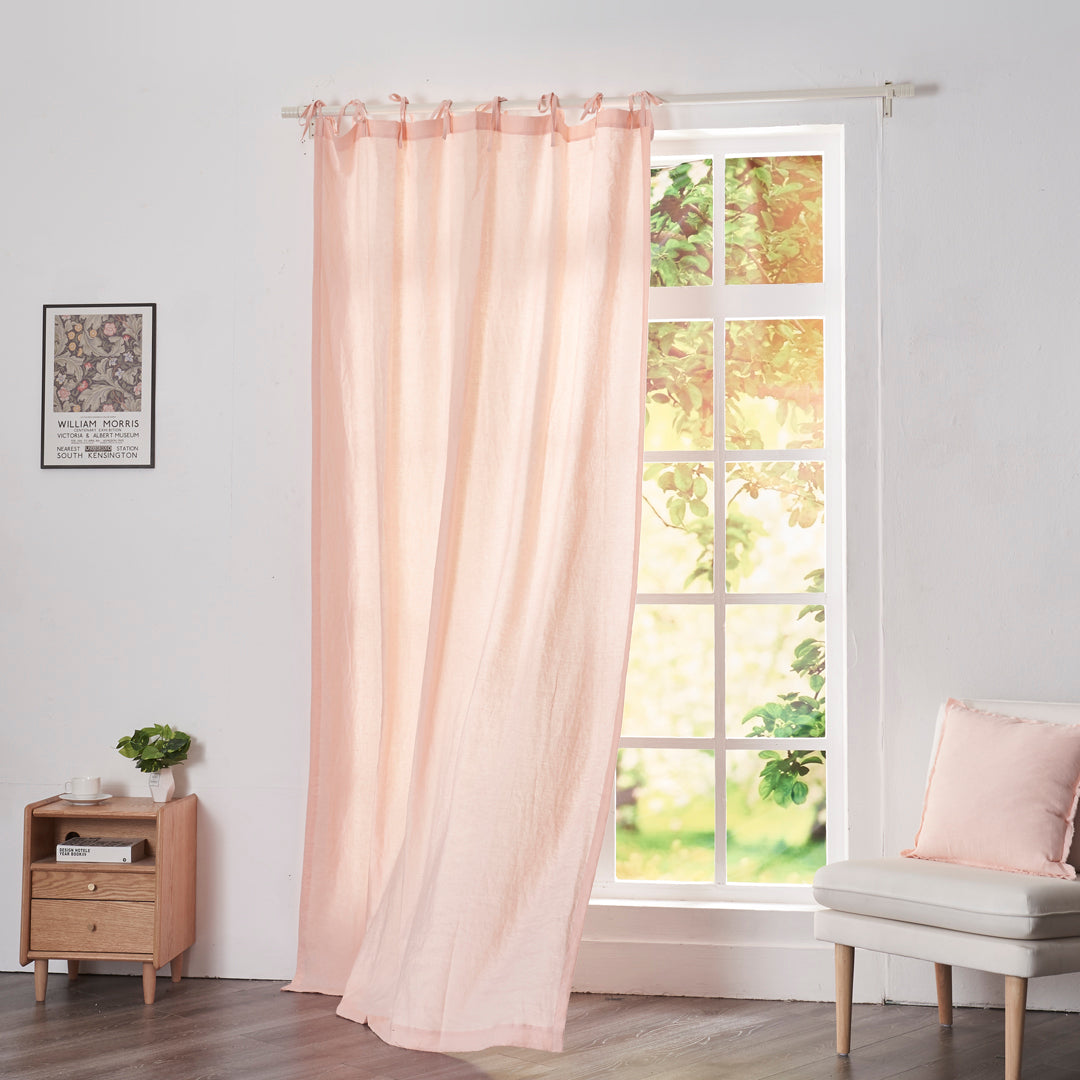 Peach linen drapery with tie tops billowing over windows