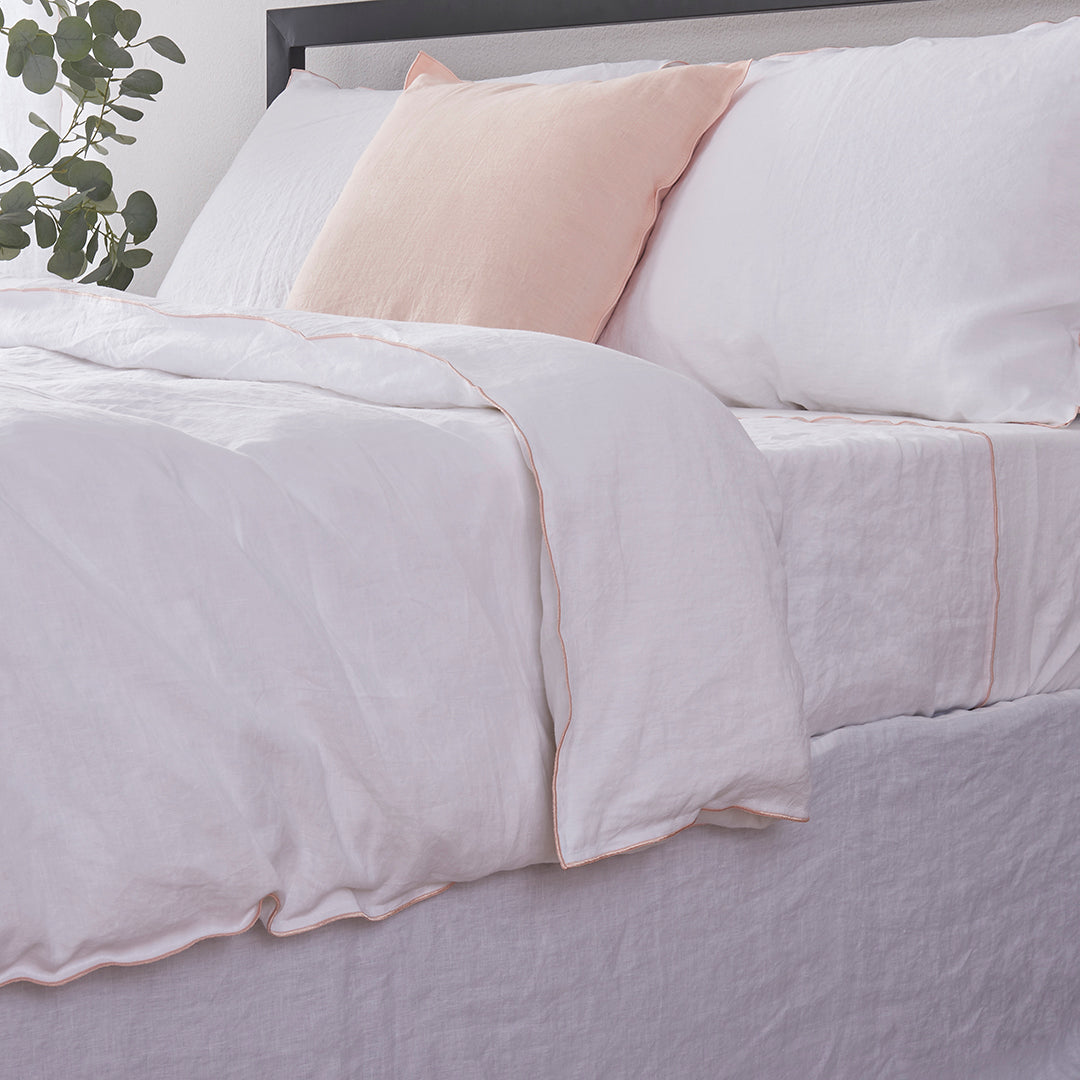 Close-up side detail of 100% linen duvet cover with peach colored edge embroidery
