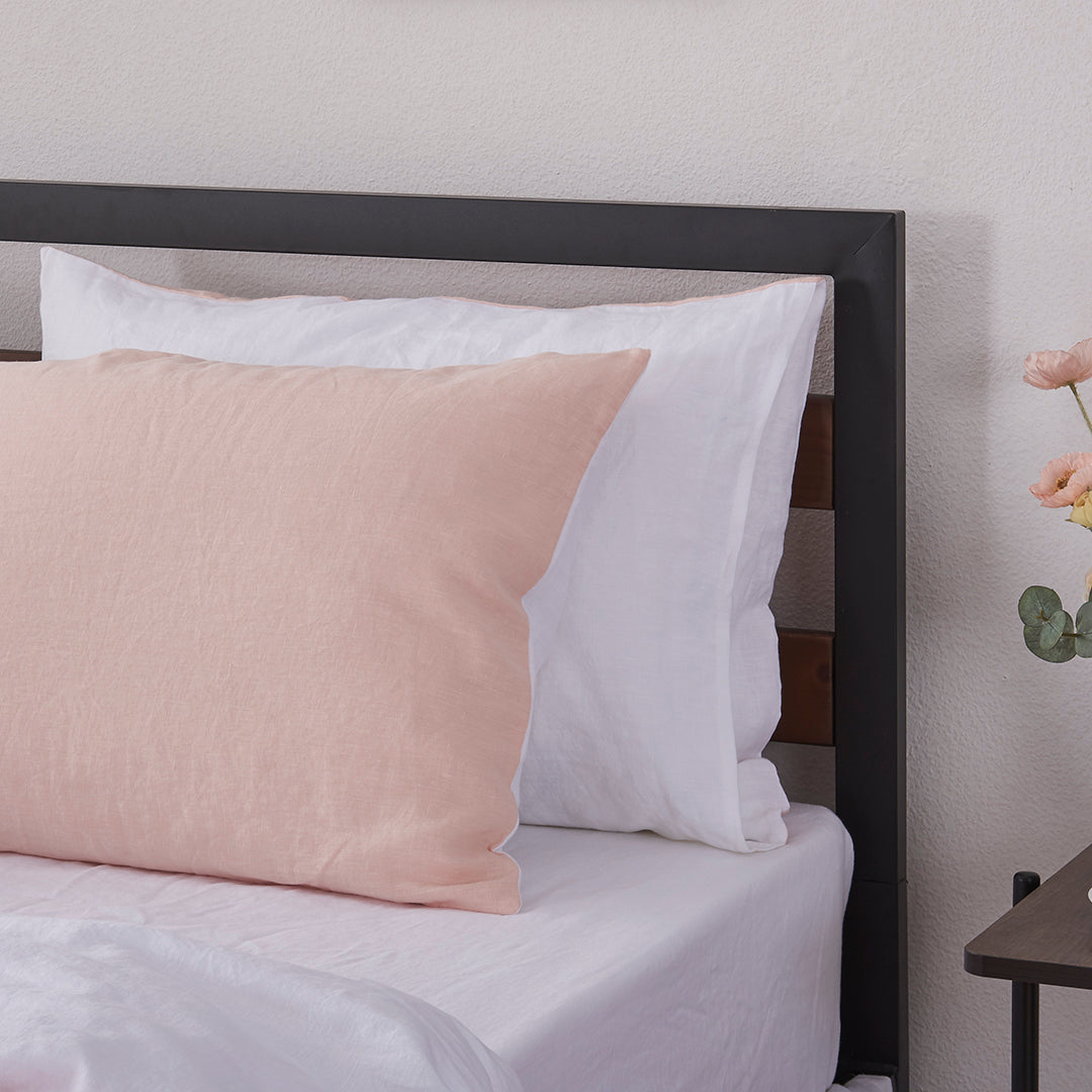 A pair of peach and white 100% linen two tone pillowcases arranged on a bed