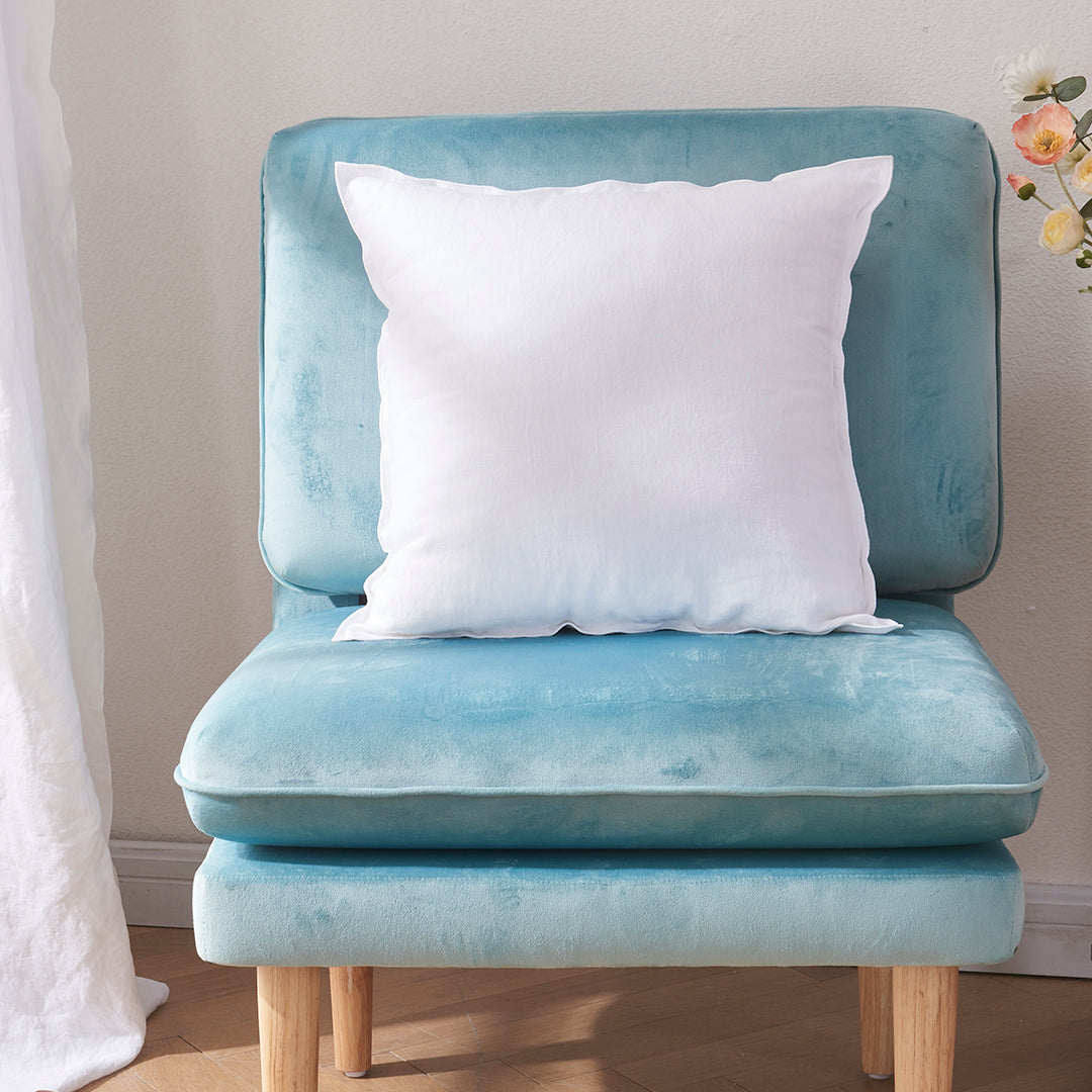 A white 100% linen edge embroidery cushion on an accent chair