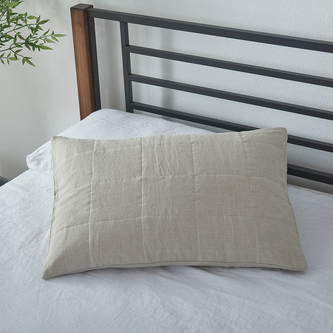 A natural 100% linen quilted pillowcase on a bed