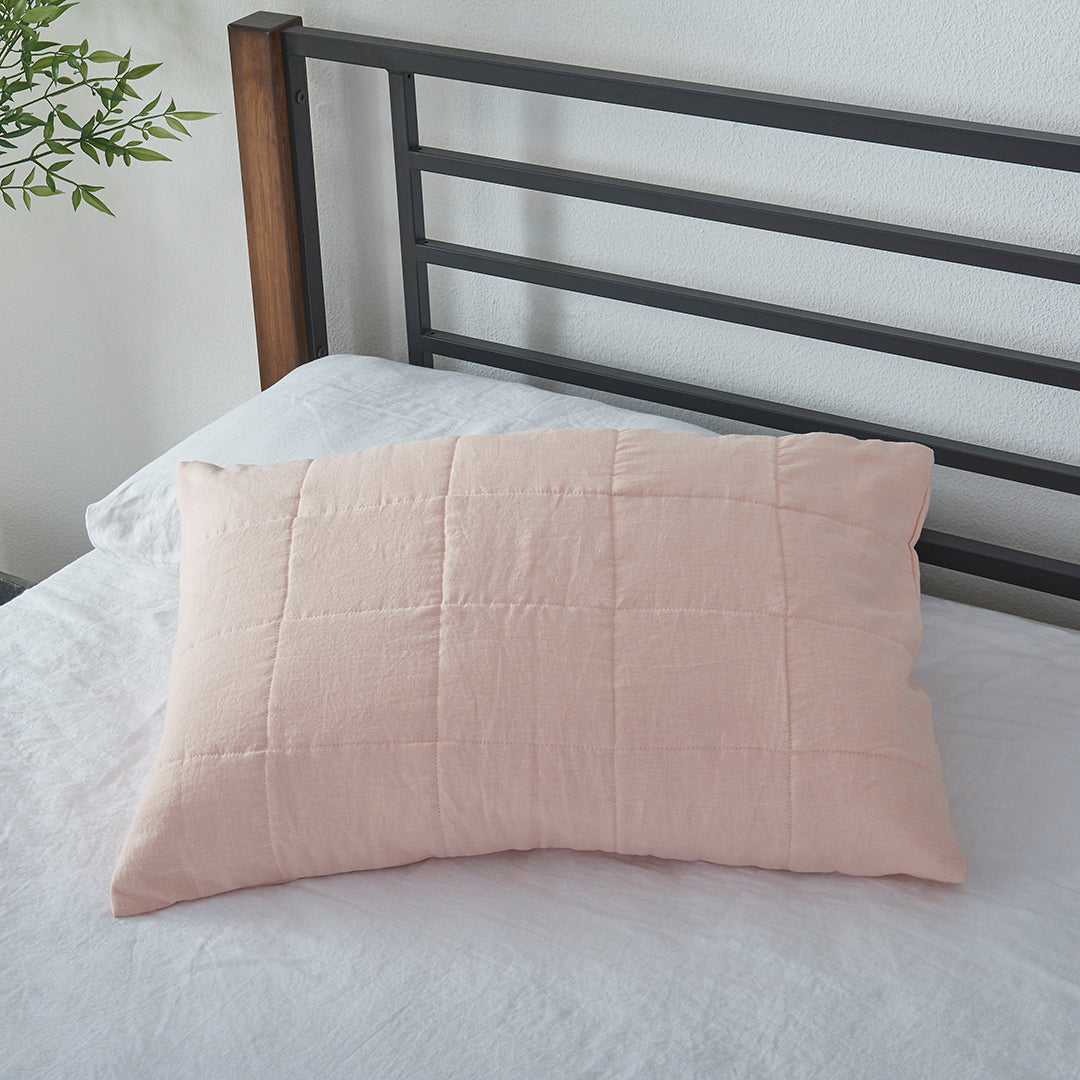 A peach 100% linen quilted pillowcase on a bed