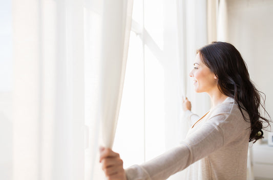 Woman Looking out Window with Linen Curtains