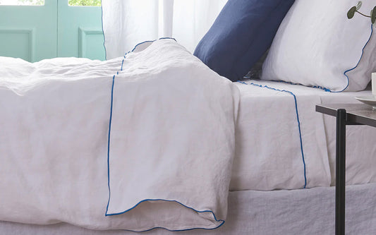 Bed with Linen Sheets and Duvet Cover with Blue Embroidered Edge
