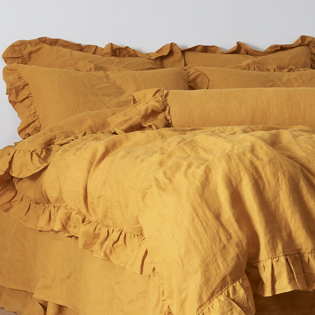 Mustard Yellow Linen Bolster Cushion with Ruffle Hem on Bed