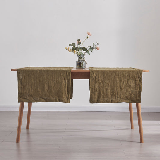 Side angle of 100% linen table runners in green olive draped over a wooden table