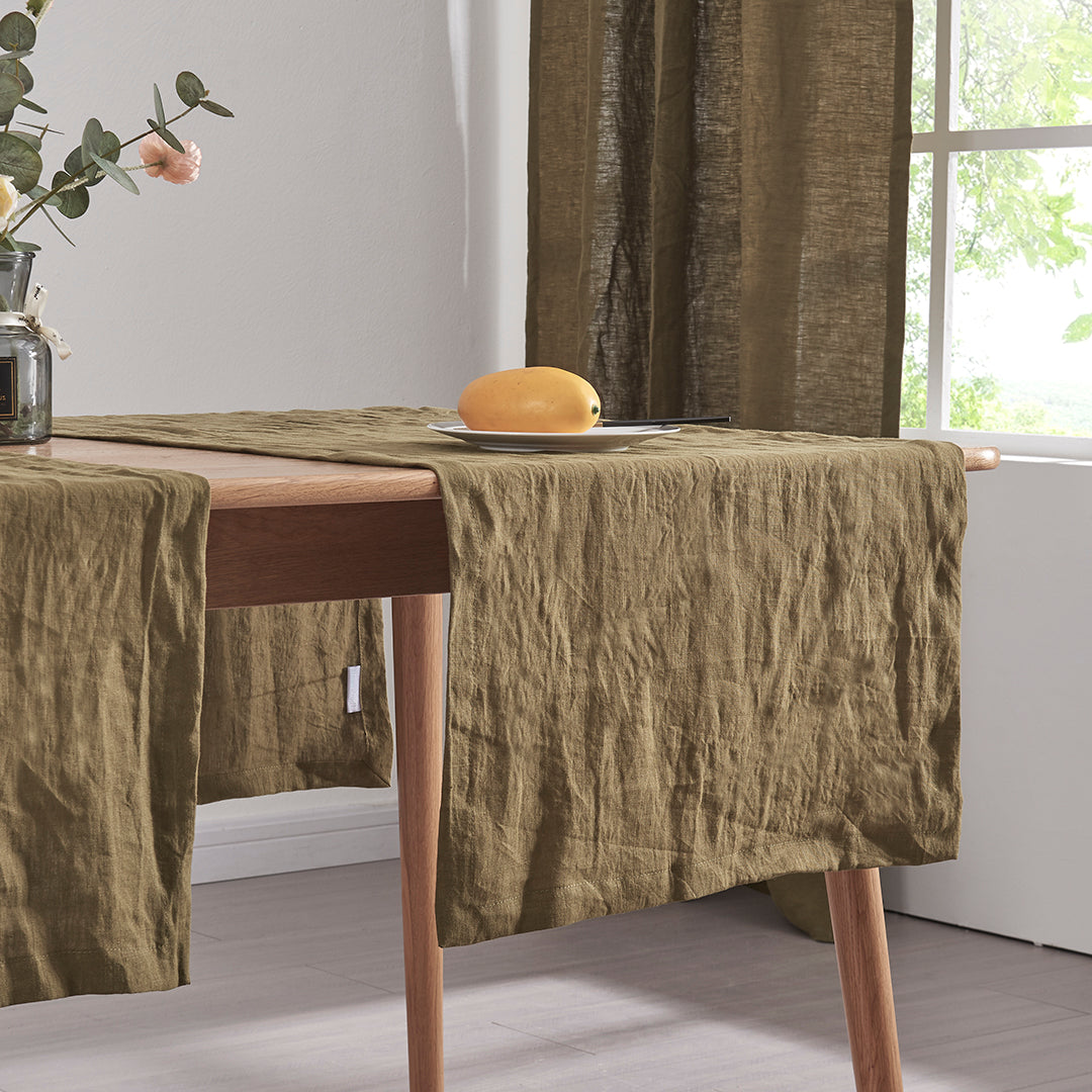 Close-up detail of 100% linen table runners in green olive draped over a wooden table