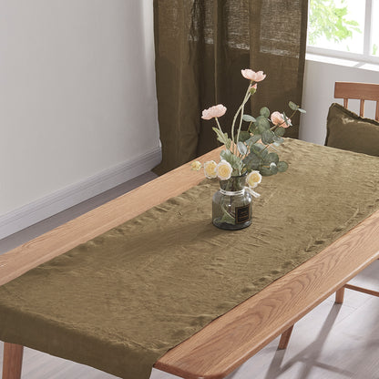 Top angle of a 100% linen table runner in green olive draped over a wooden table