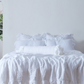 Optic White Linen Bolster Cushion on Bed with Ruffle Hem 