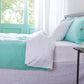 Side angle of 100% linen two tone duvet cover in aqua green and white draped over a bed