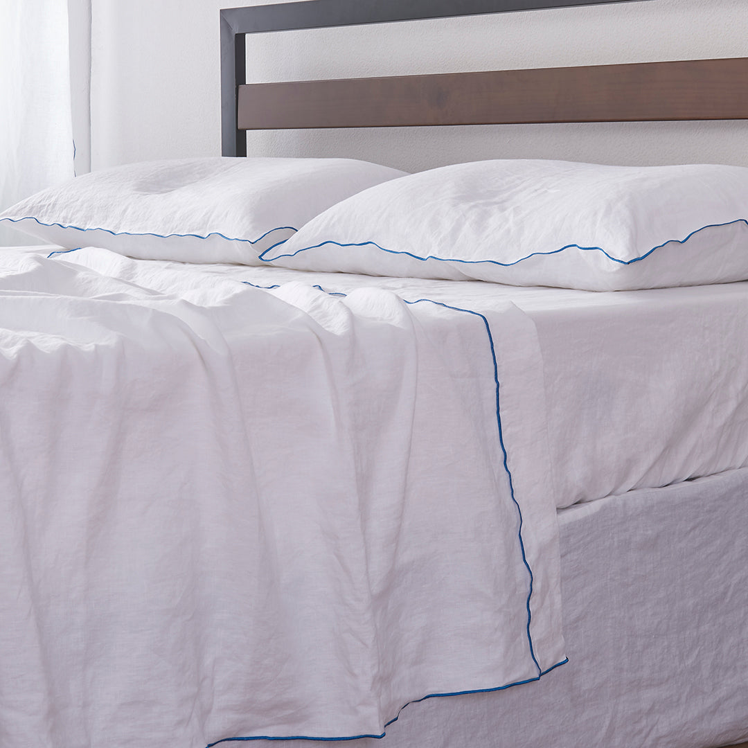 White Linen Flat Sheet with Brilliant Blue Edge Detail on Bed