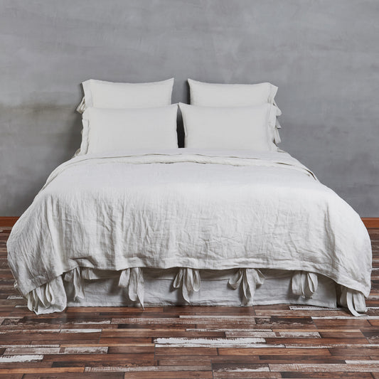 A cool grey colored 100% linen duvet cover with bow ties on a made bed