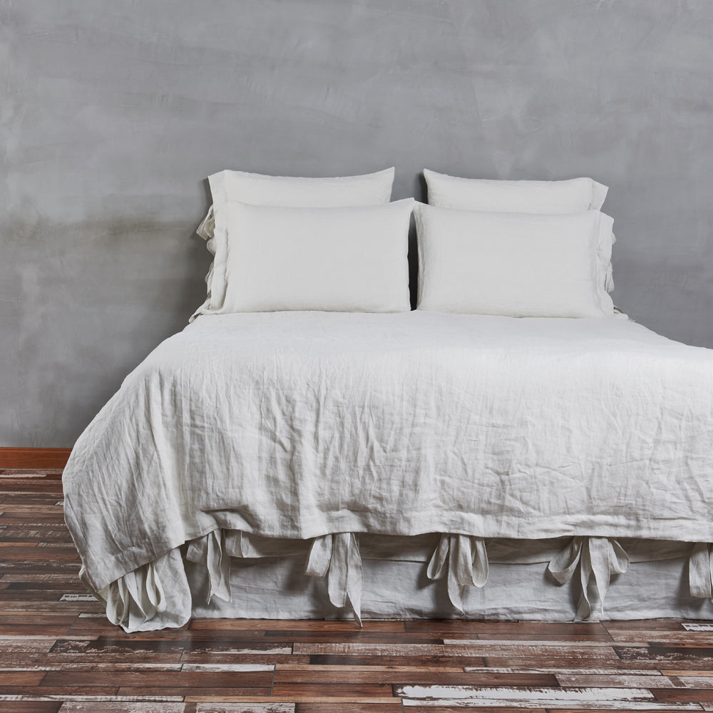 A bed with a cool grey colored 100% linen duvet cover with bow ties