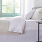 Side angle of 100% linen two tone duvet cover in cool grey and white draped over a bed