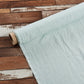 A roll of 100% linen pale blue fabric sample on the floor