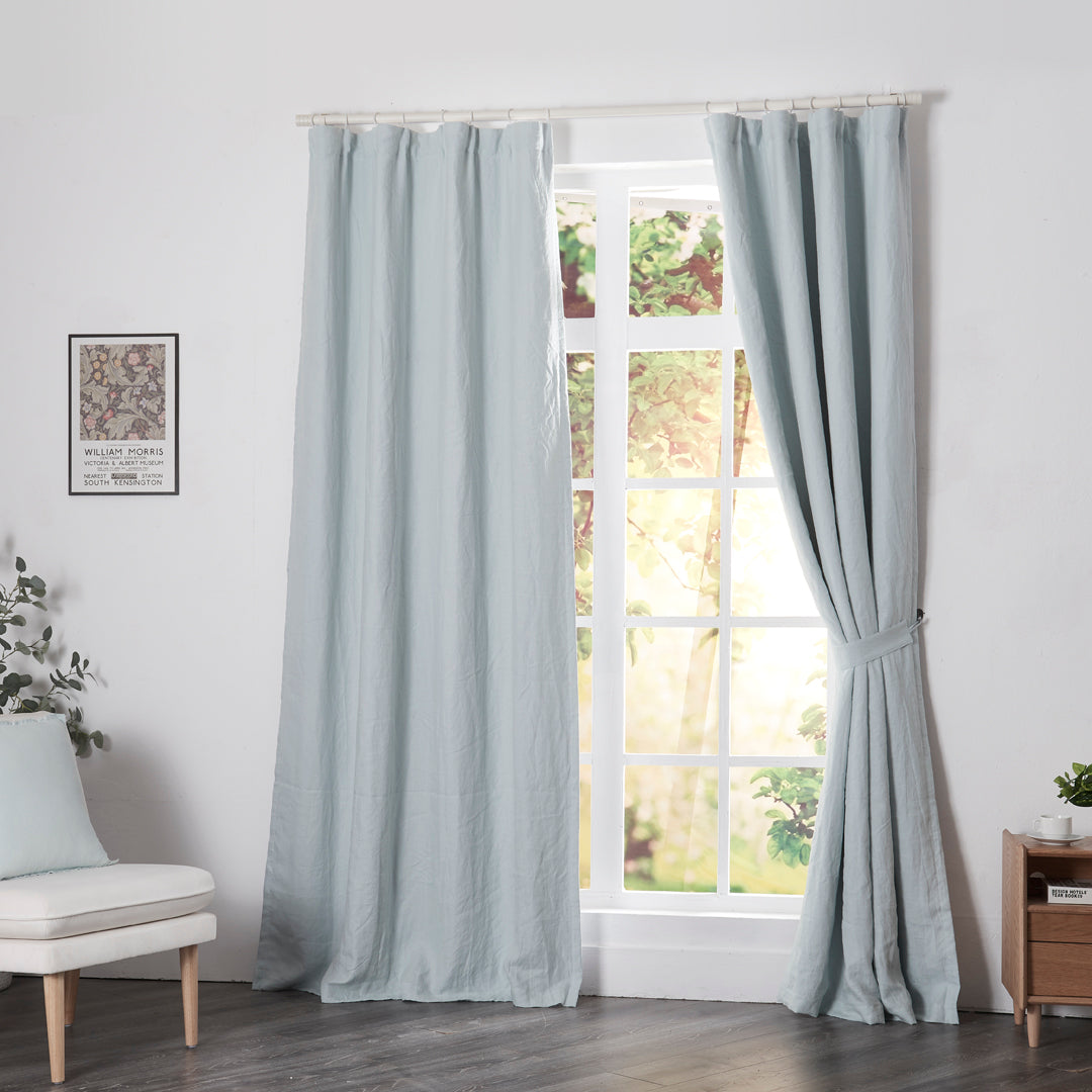 Pale blue linen drapery with blackout lining hanging over windows