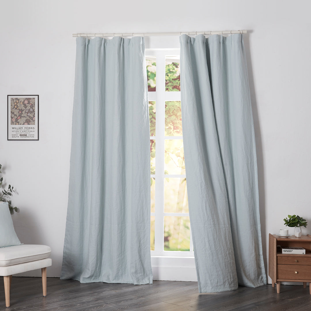 Pale blue linen drapery with blackout lining billowing over windows