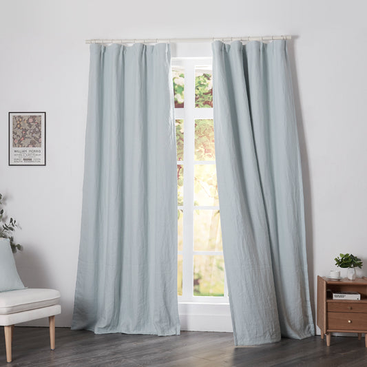 Pale blue linen drapery with blackout lining billowing over windows