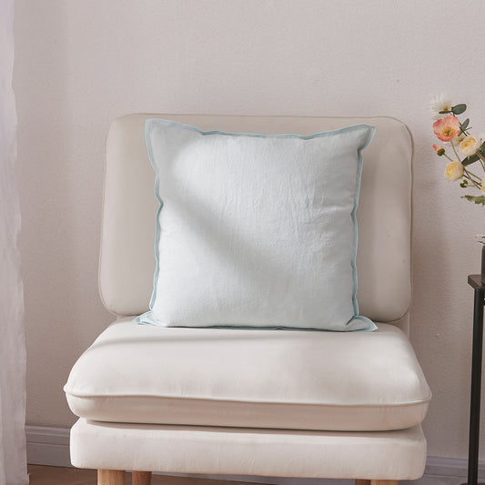 A pale blue 100% linen edge embroidery cushion on an accent chair