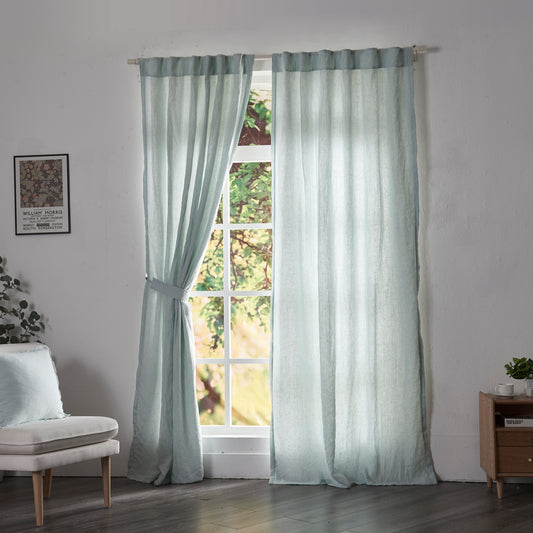 Pale blue linen drapery with cotton lining hanging over windows