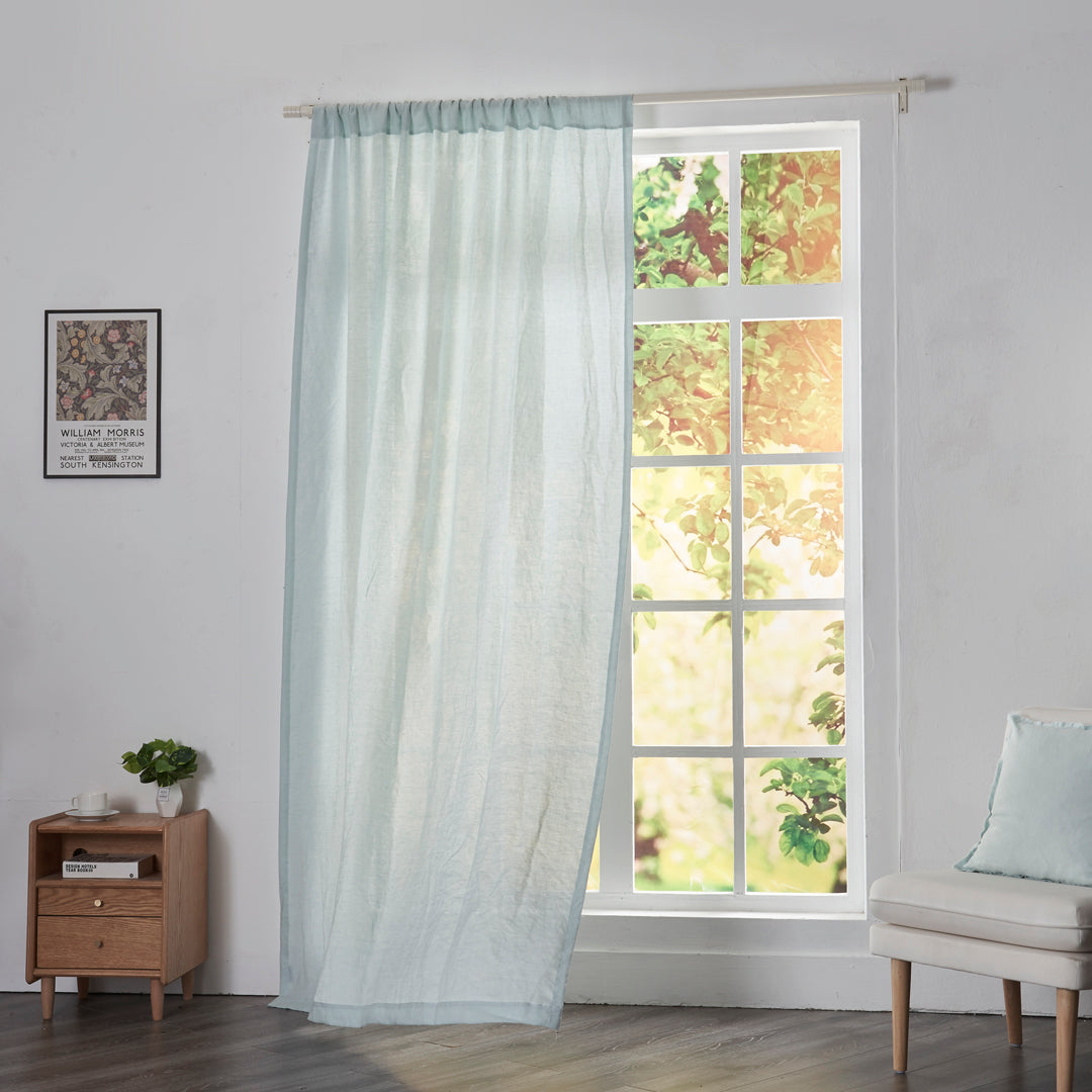 Pale blue linen drapery with rod pockets billowing over windows
