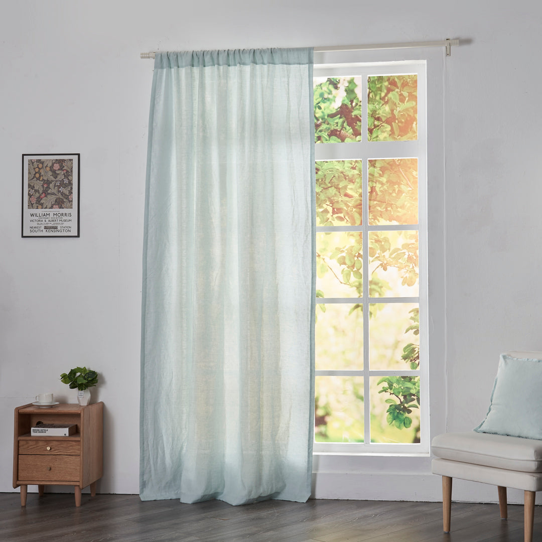 Pale blue linen drapery with rod pockets hanging over windows