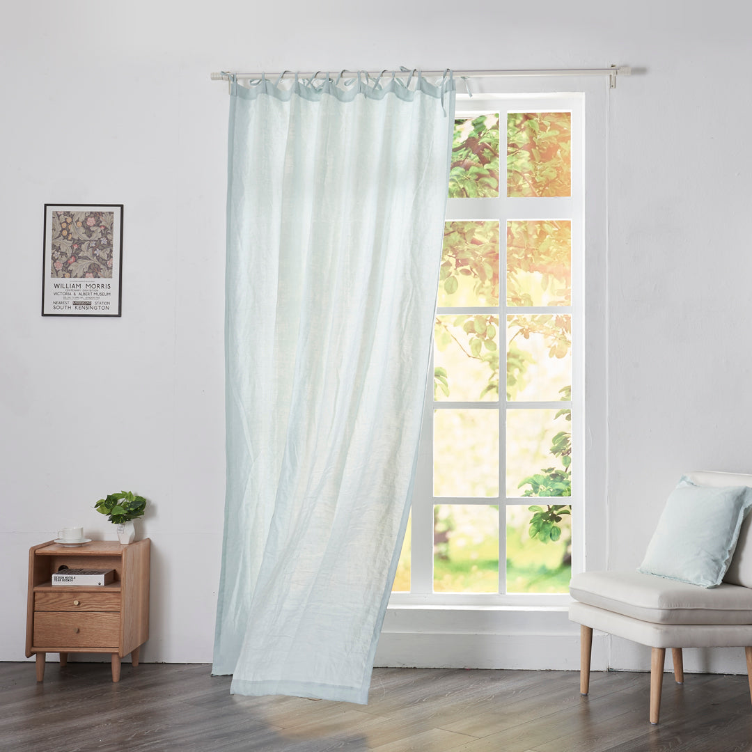 Pale blue linen drapery with tie tops billowing over windows