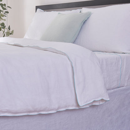 Close-up side detail of 100% linen duvet cover with pale blue colored edge embroidery