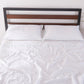Top angle of 100% linen flat sheet with pale blue colored edge embroidery laid over a bed