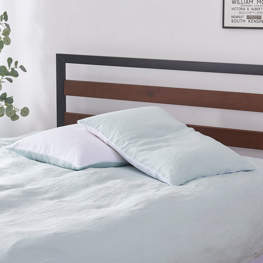 A pair of pale blue and white 100% linen two tone pillowcases stacked on a bed
