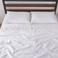Top angle of 100% linen flat sheet with peach colored edge embroidery laid over a bed