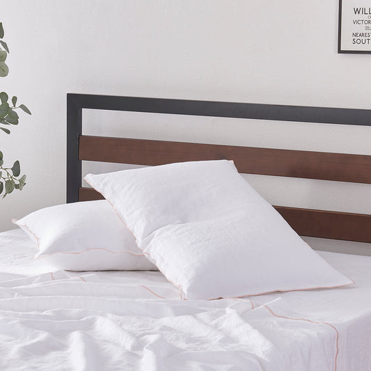 A pair of stacked 100% linen pillowcases with edge embroidery in peach