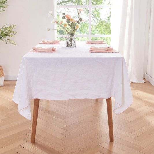 Side angle of peach edge embroidered linen tablecloth draped over a wooden table