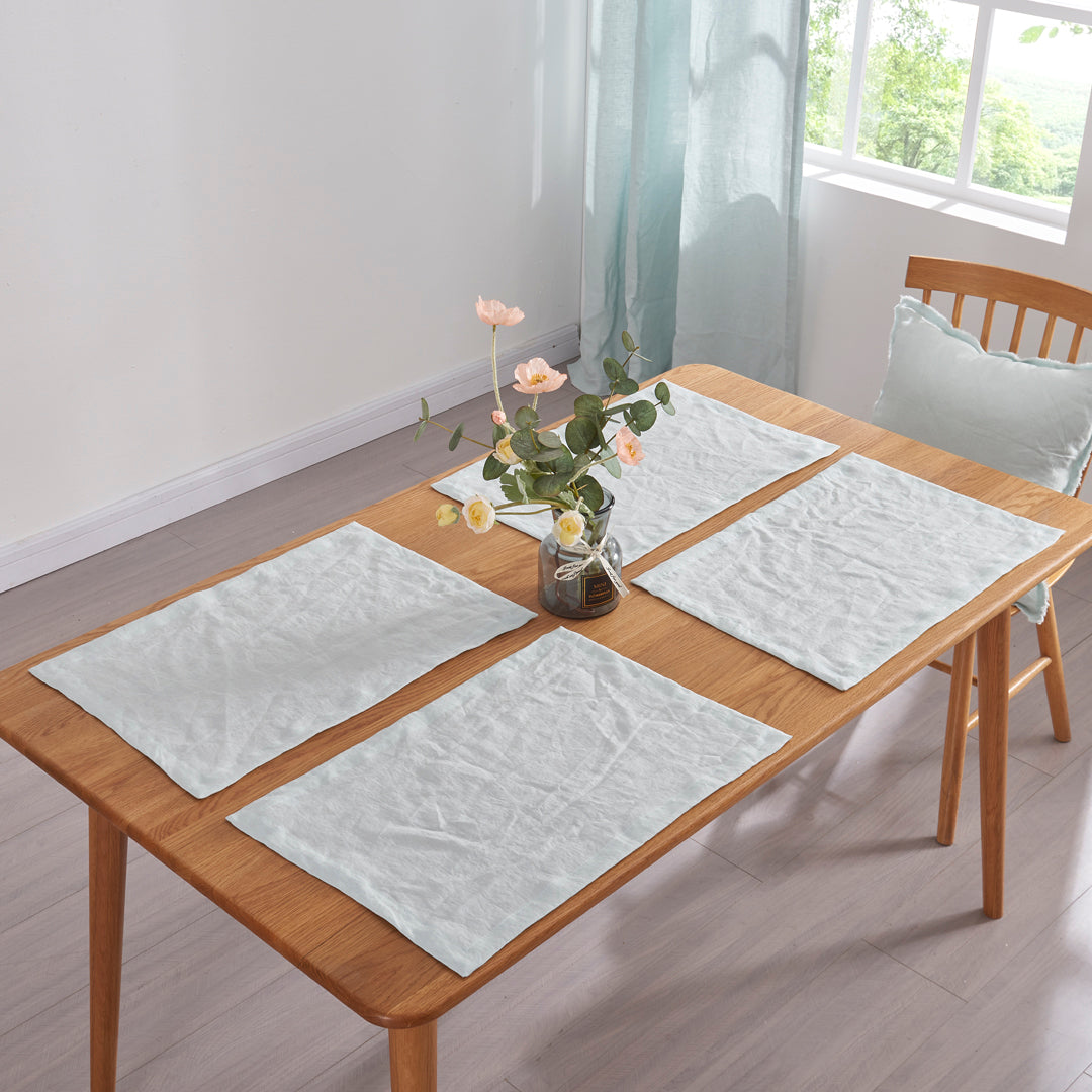 A set of 100% linen pale blue plain placemats on wooden table