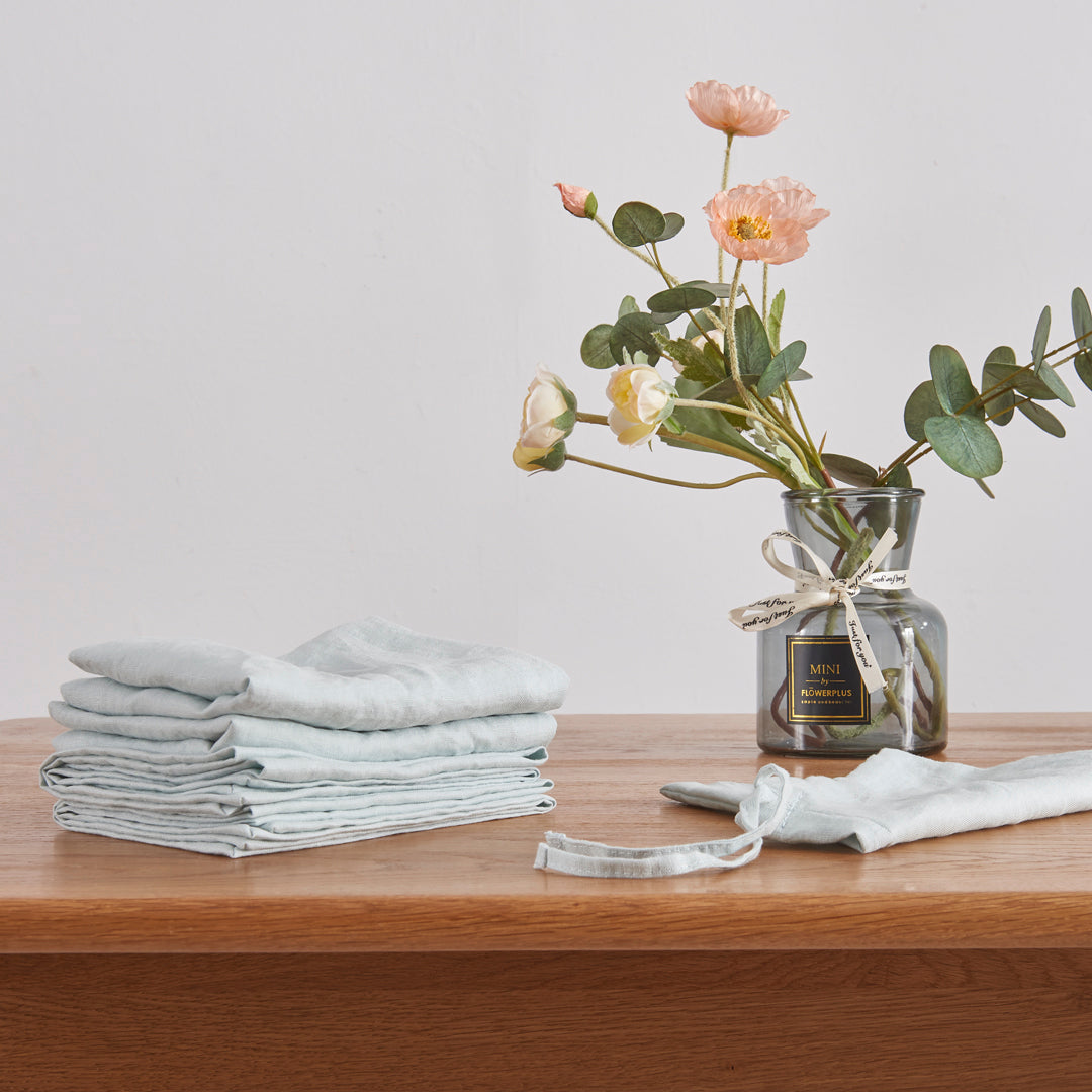 A stack of 100% linen pale blue placemats on wooden table