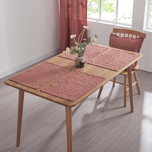Rust red 100% linen placemats set on a wooden dining table with flower vase