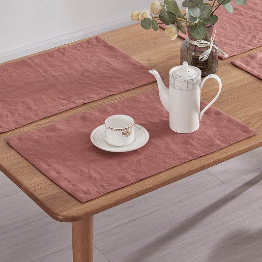 Close-up of rust red 100% linen placemats set on a wooden dining table with tea set