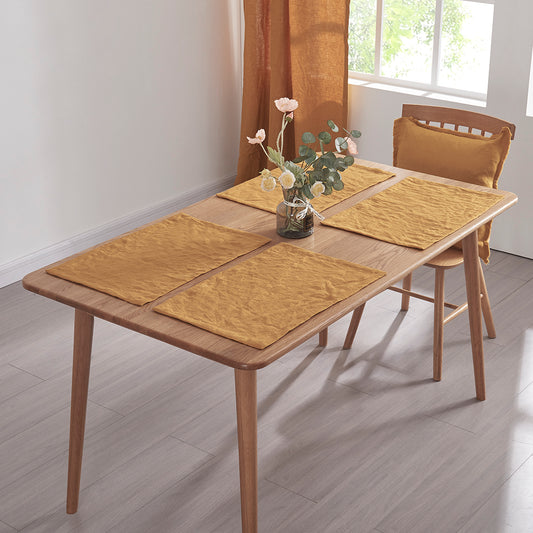 A set of mustard placemats made from 100% linen on a wooden dining table
