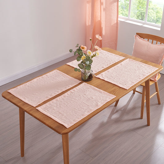 Peach 100% linen placemats set on a wooden dining table with flower vase