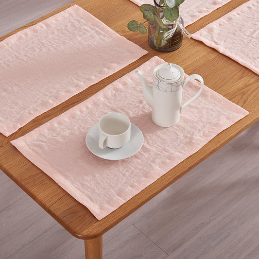 Close-up of peach 100% linen placemats set on a wooden dining table with tea set
